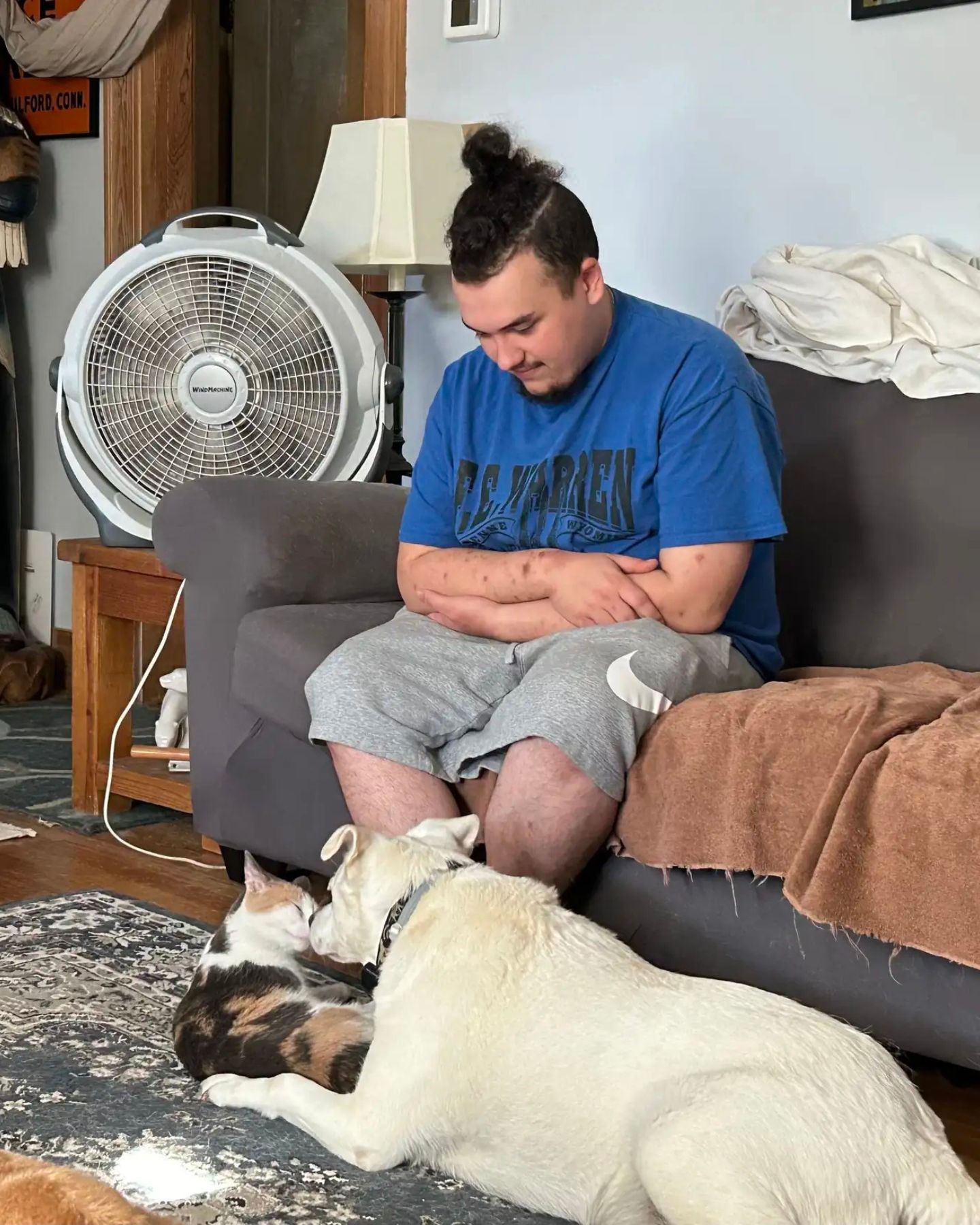 man sitting with cat and a dog