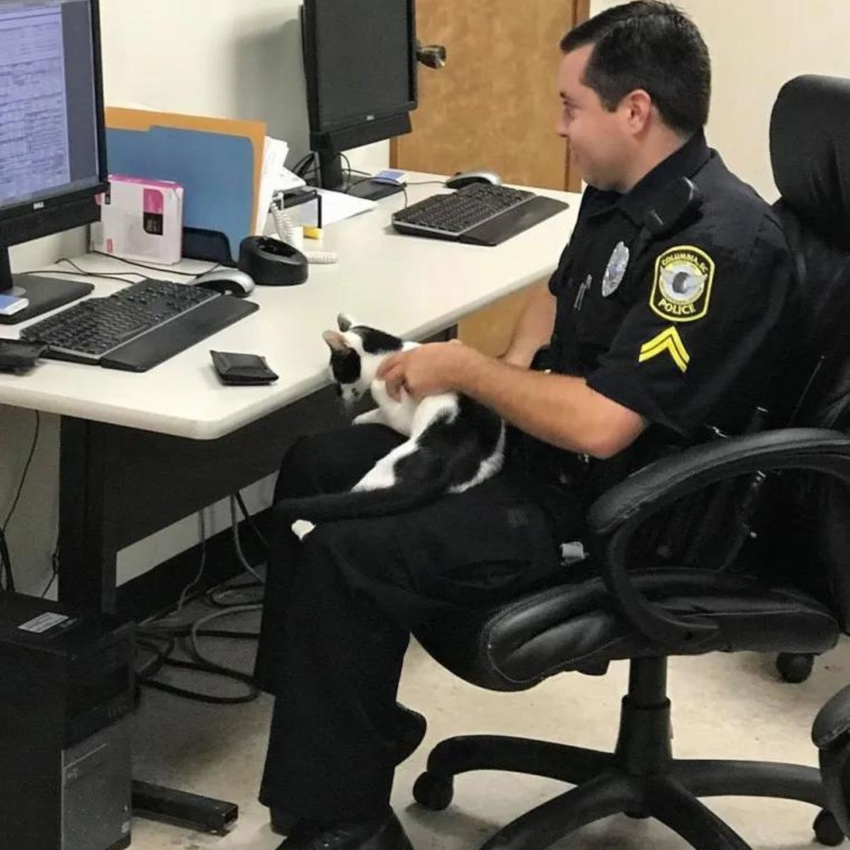 cat is sitting in the policeman's arms at the table