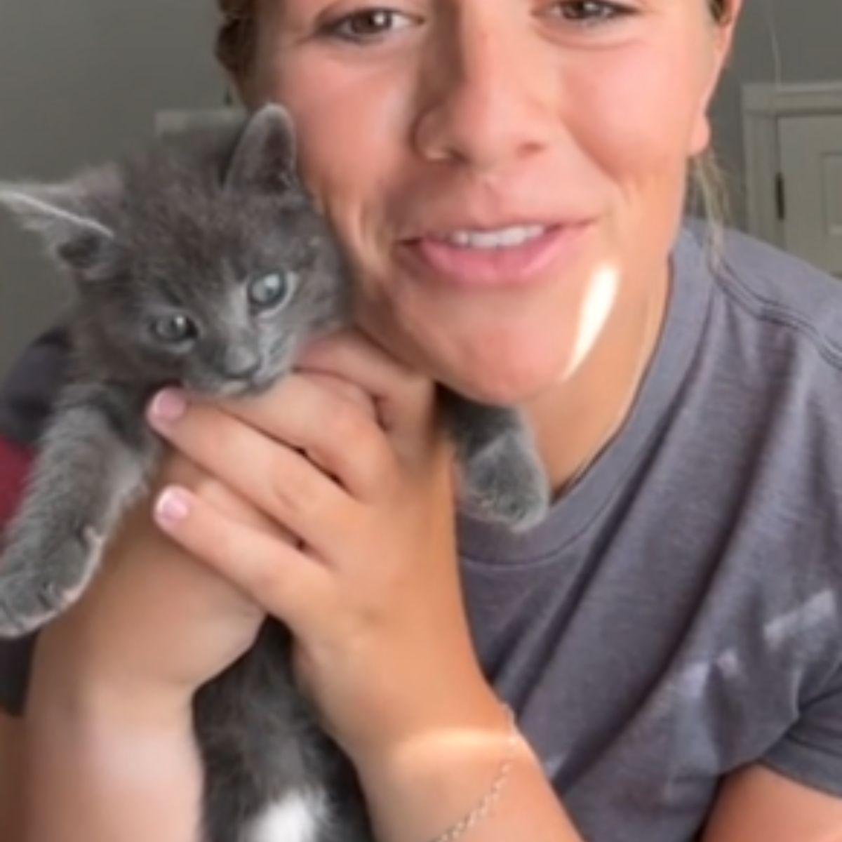 gray kitten is cuddling with a woman