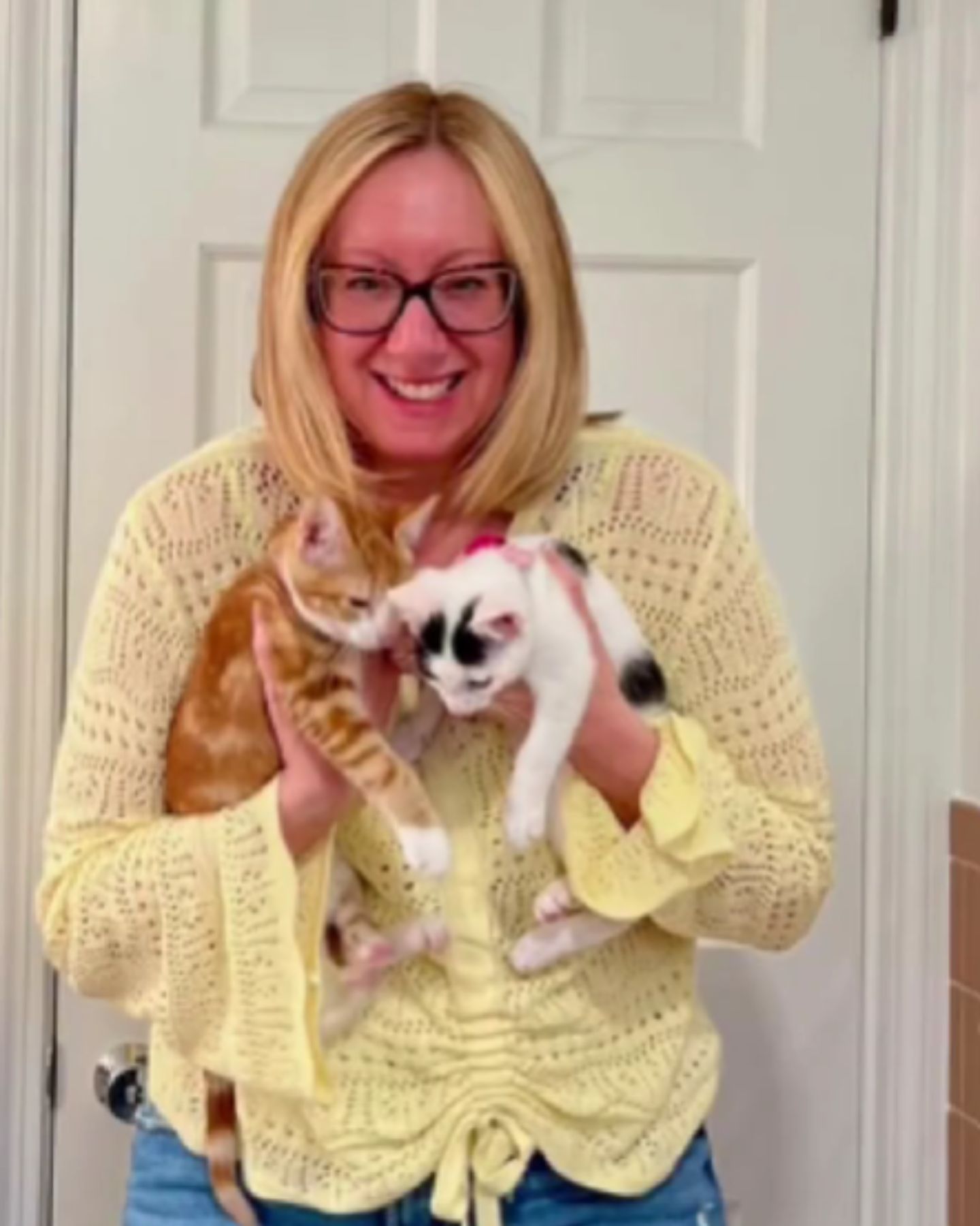 woman is holding two kittens in her hands