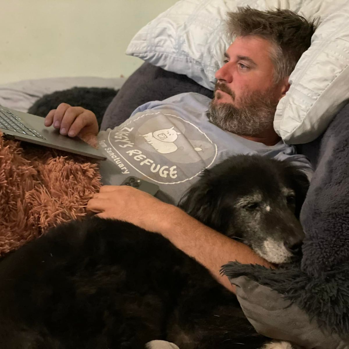 black dog is lying down with a man in the house