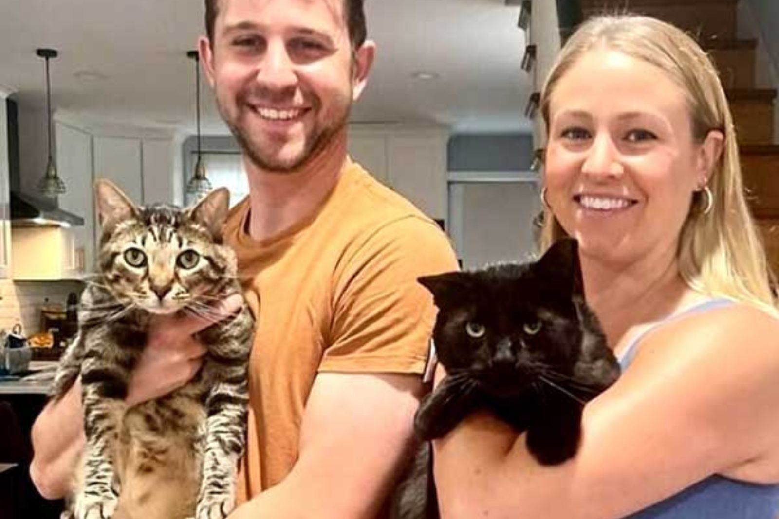 man and woman each holding a cat