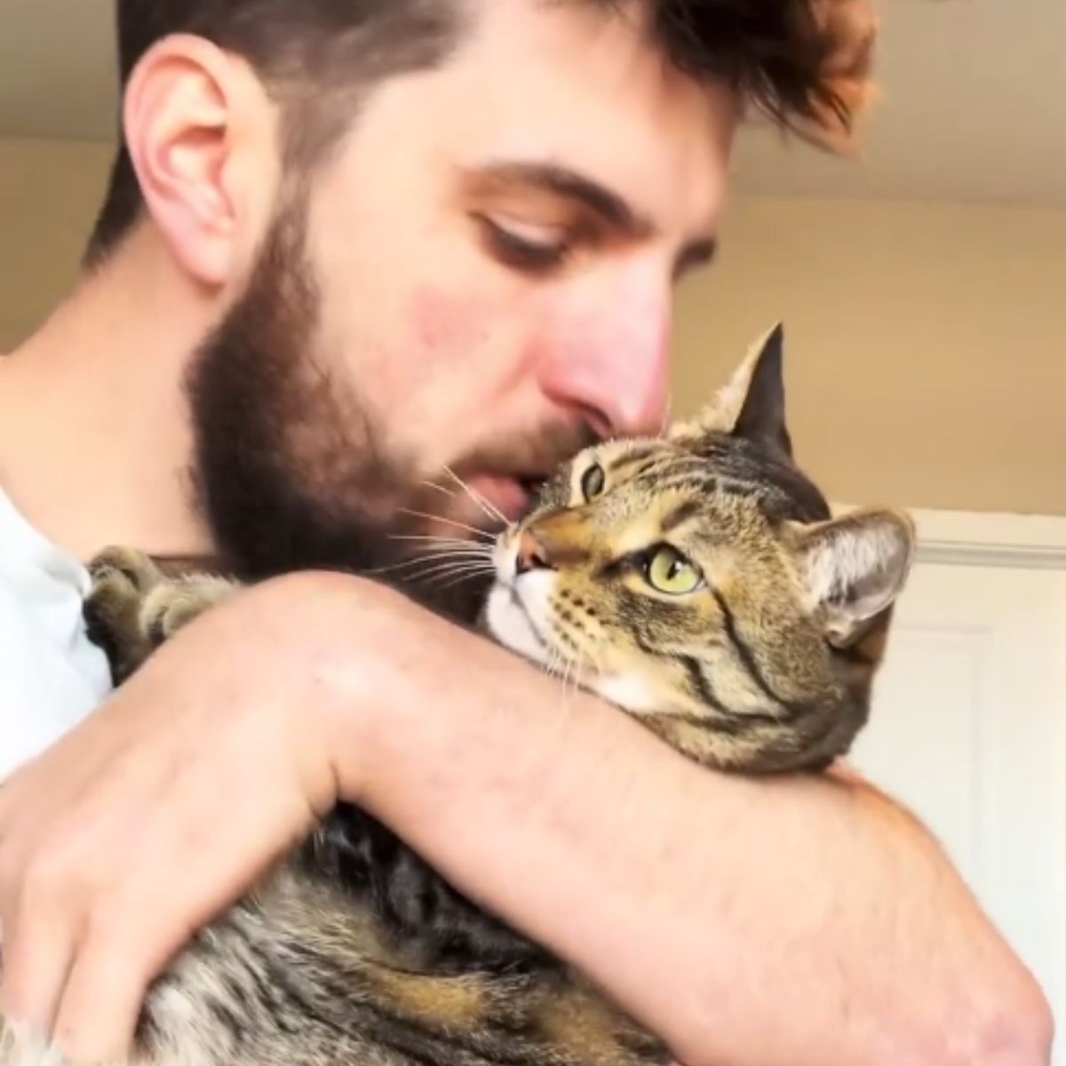 man cuddling with cat
