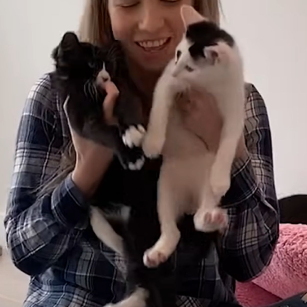 woman holding up two kittens