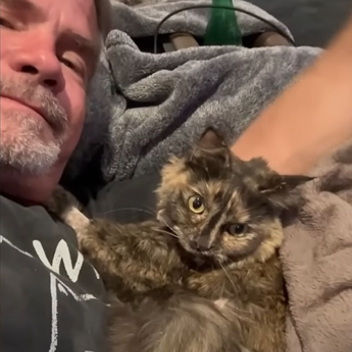 man cuddles cat in cage