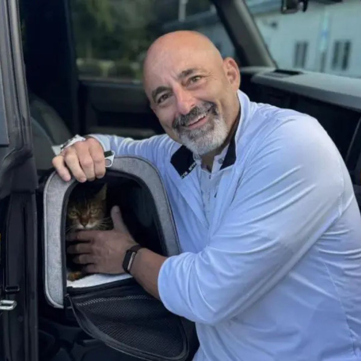 man petting cat in carrier