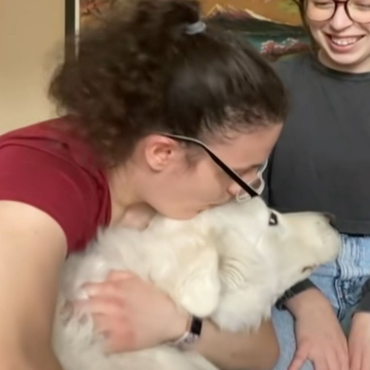 woman kisses white dog