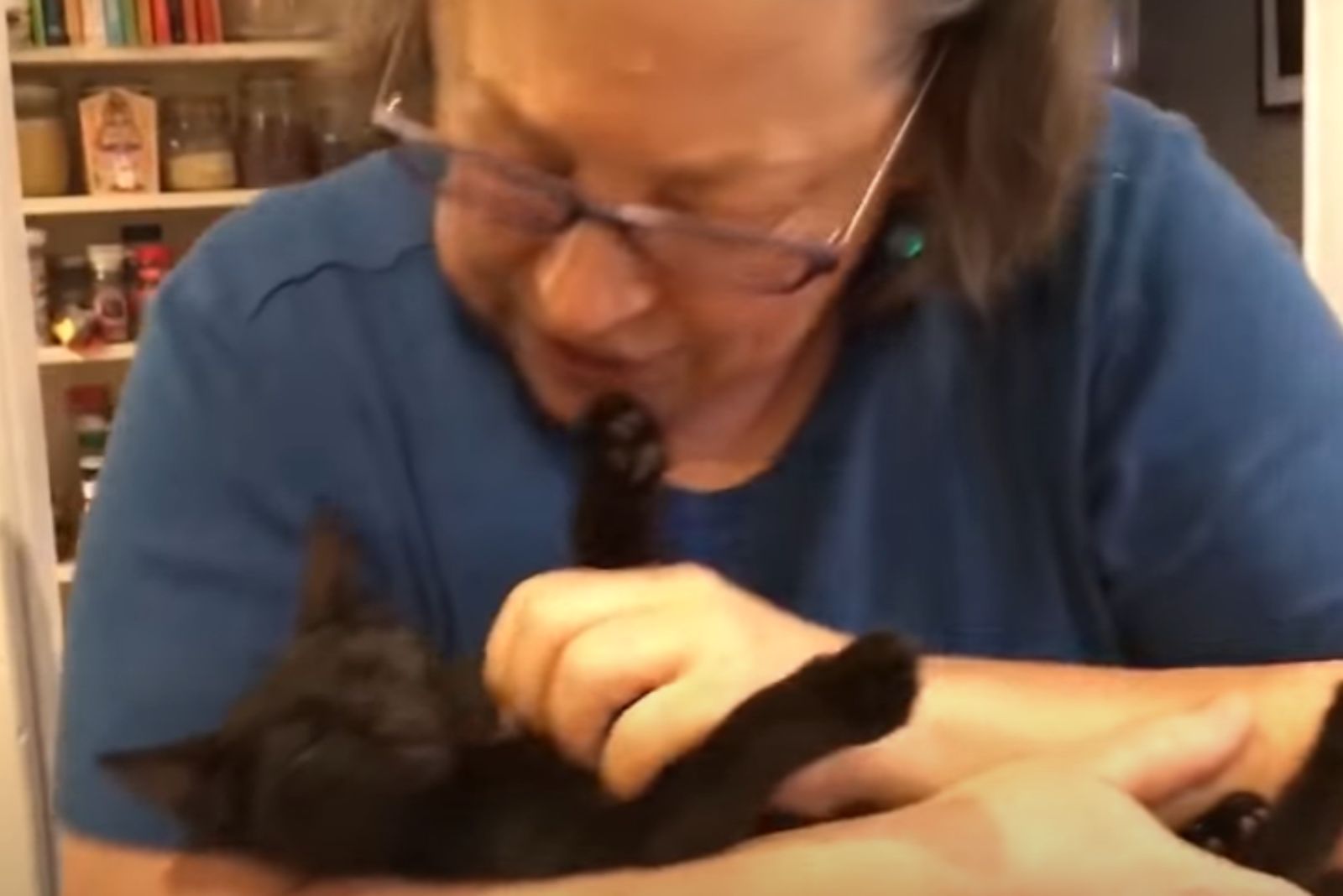 woman strokes a black kitten