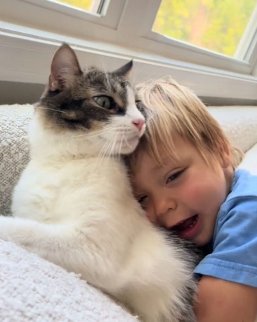 The boy is lying leaning against the cat