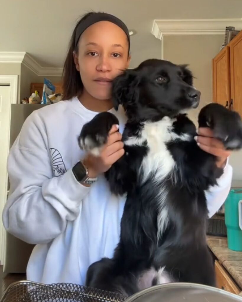 The girl is holding the dog by the paws