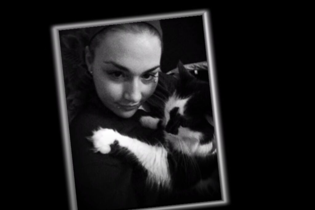 a girl takes a picture with a cat in her arms