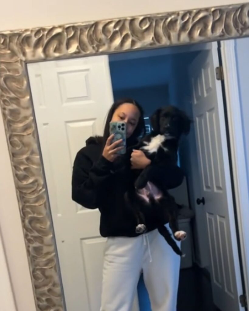 a girl takes a picture with a dog in the mirror