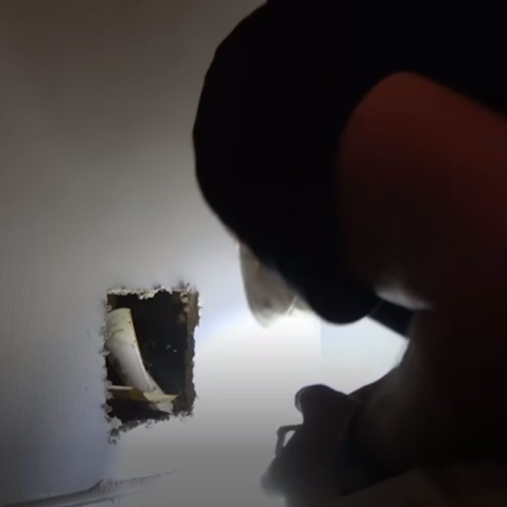 a man looks through a hole in the wall