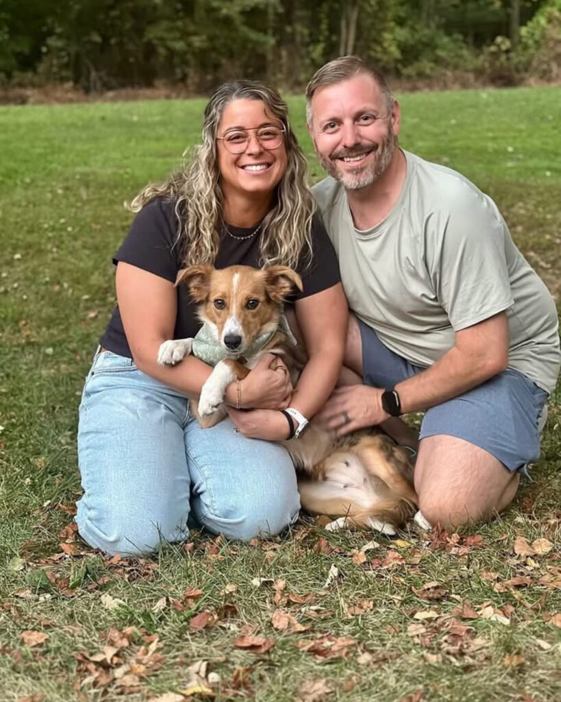man and woman with a dog hugging