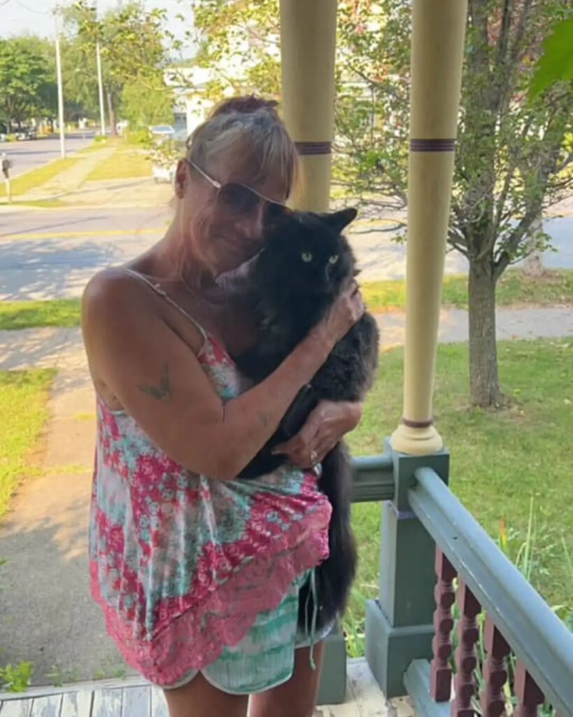woman holding a black cat in her hands