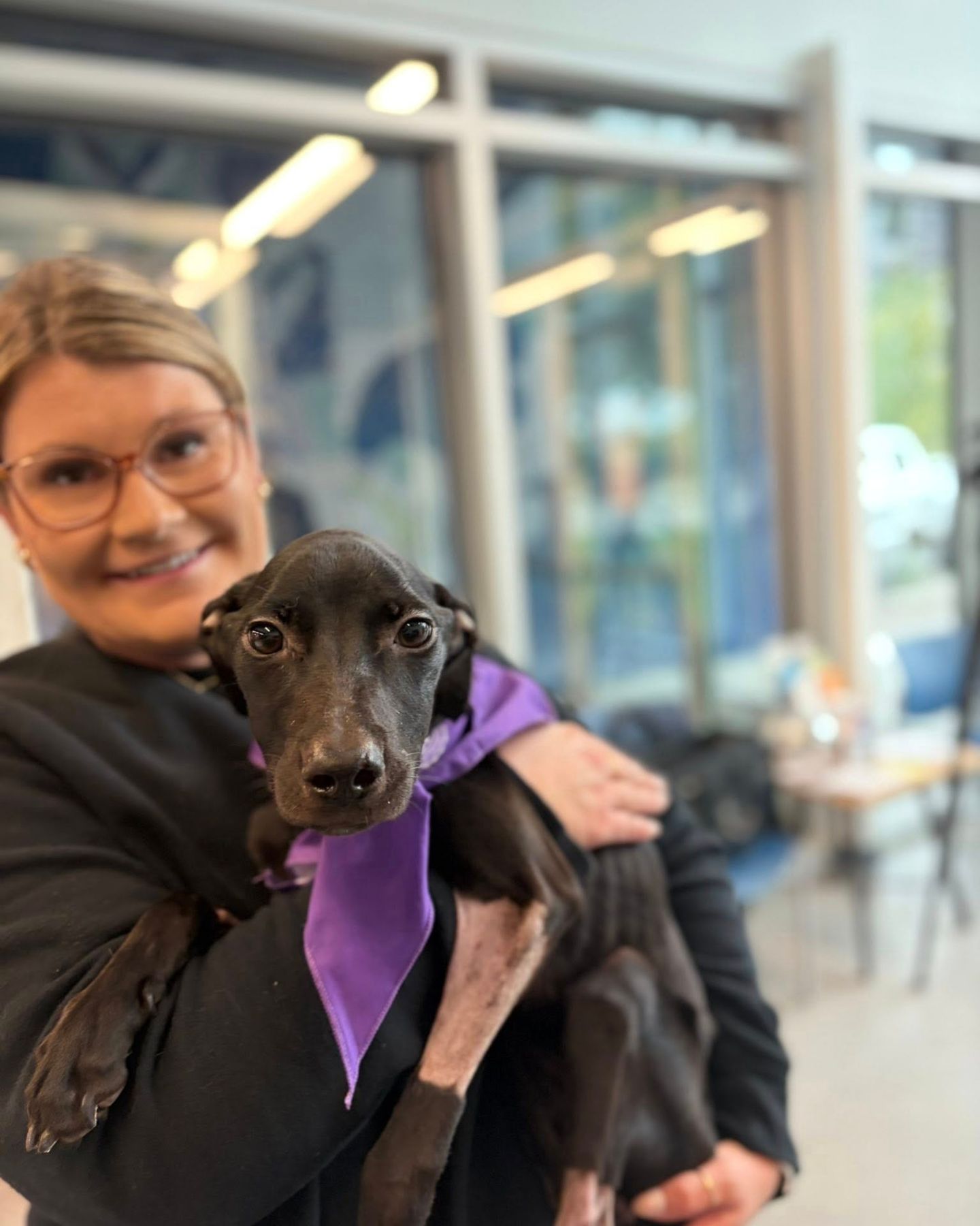 woman holding a black puppy