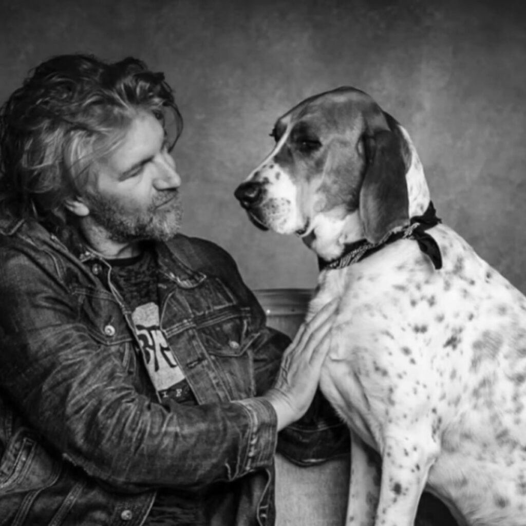 a man sits next to a dog