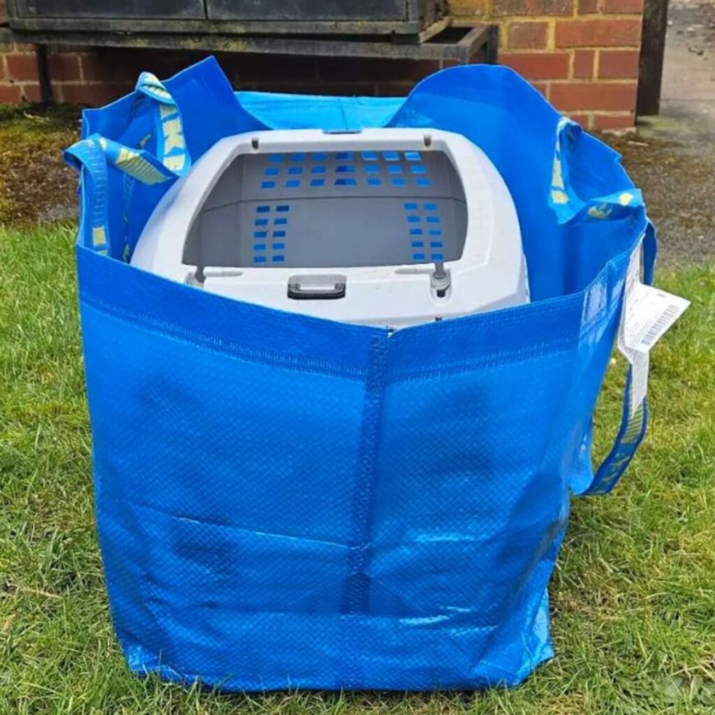 cage in a blue large bag on the grass