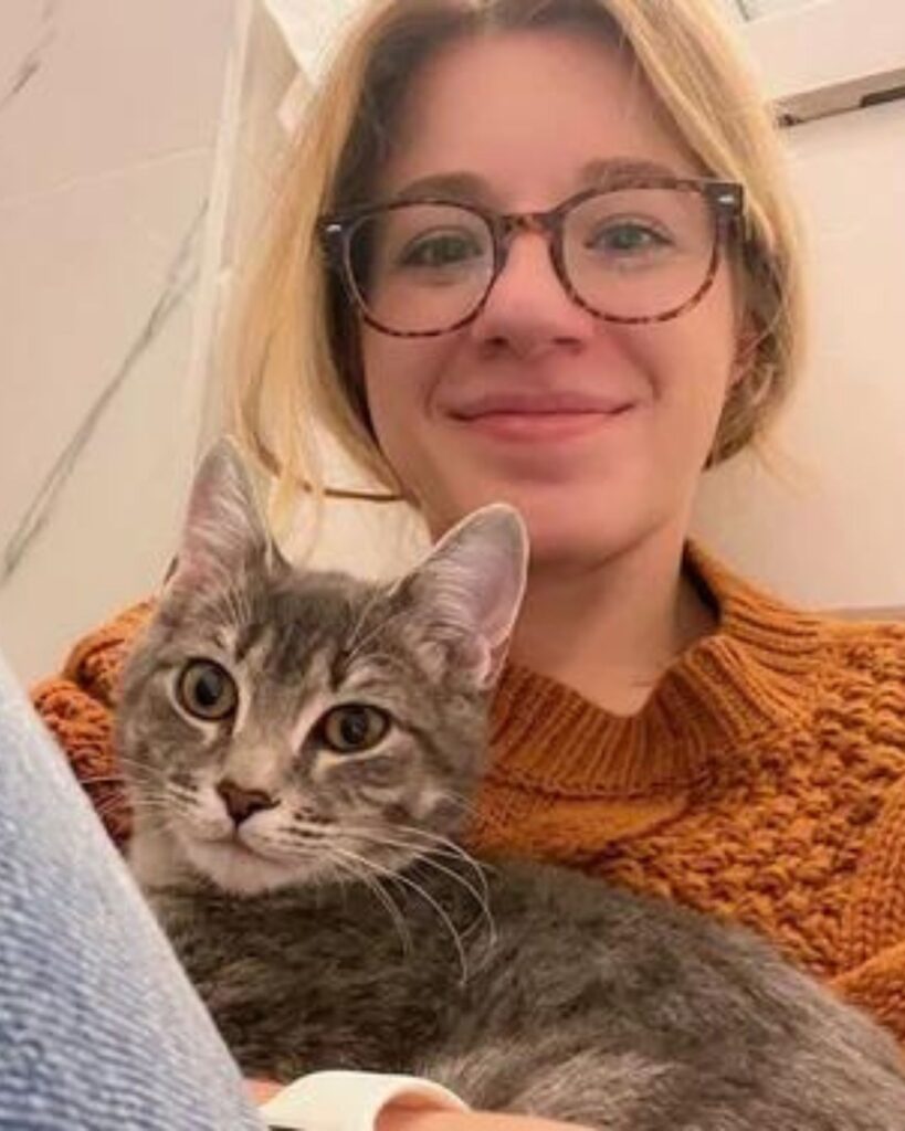 girl with glasses holding a cat in her hand