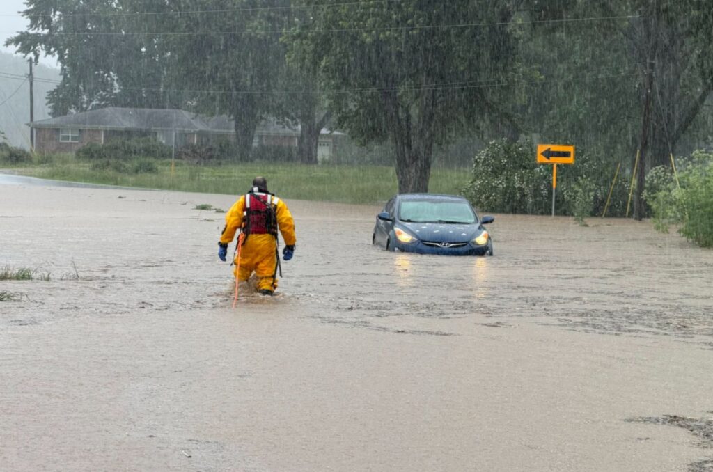 firefighter approaching a car stuck in floodwaters