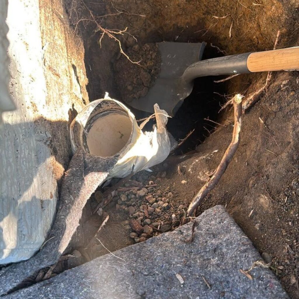 shovel digging around a pipe
