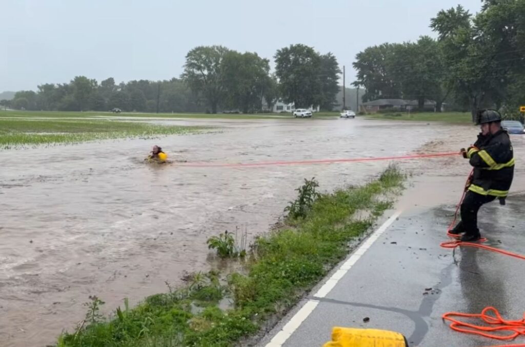 firefighter holding his colleague in floodwaters by a rope