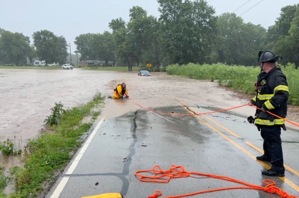 firefighters pulling something out from floodwaters