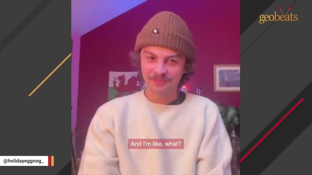 A man with a mustache wearing a brown knit beanie and a cream-colored sweater looking forward.