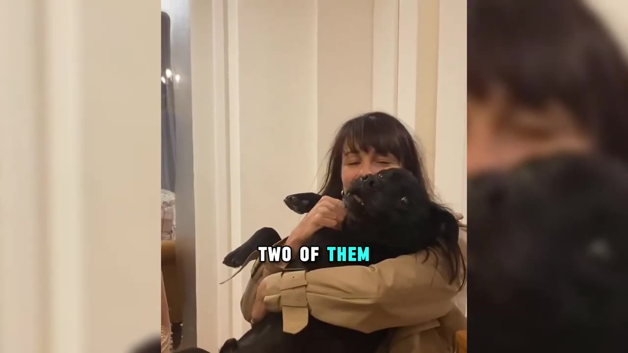 A woman with dark hair smiles as she holds a black dog in her arms.