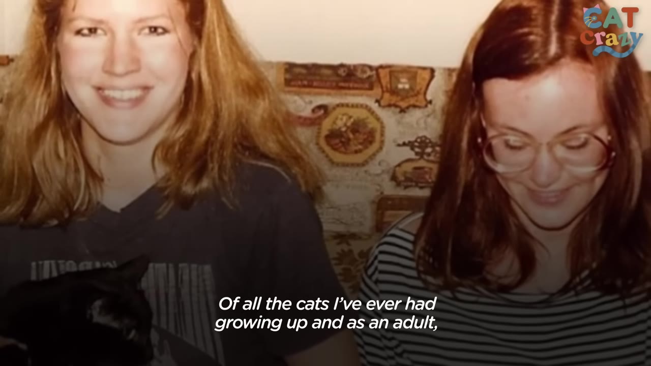 A vintage photograph of two smiling young women, with one holding a black cat in her lap.