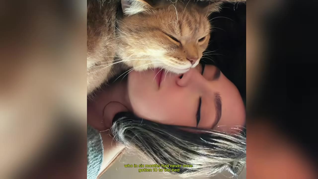 A close-up, upside-down view of a woman sleeping with her eyes closed as a fluffy brown cat rests its head gently against her chin.