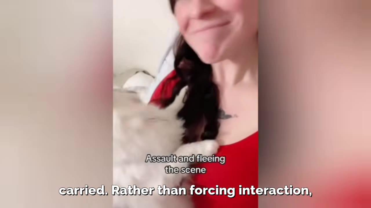 A close-up of a smiling woman in a red shirt as a fluffy white cat cuddles against her chest.