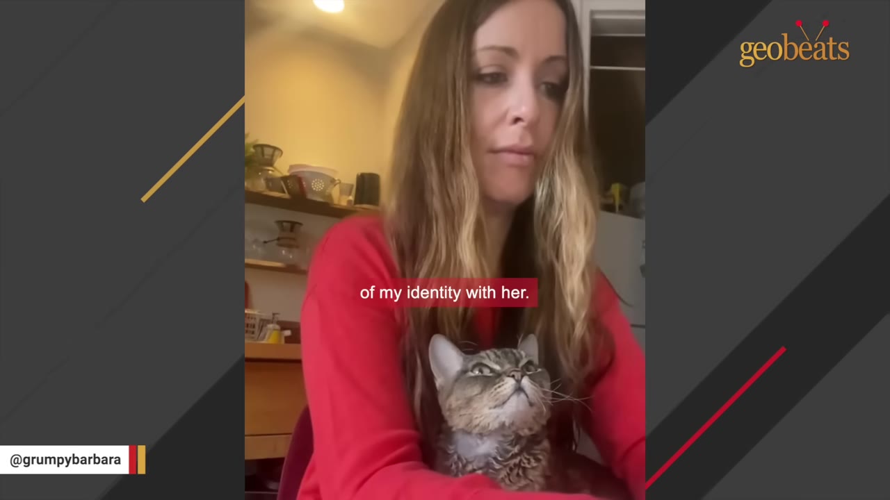 A woman in a red sweater looks down affectionately at a tabby cat sitting in her lap, who is looking up at her.