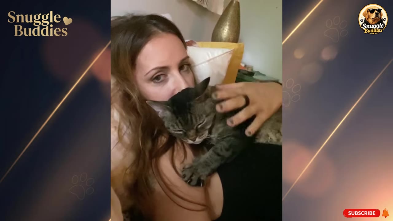 A tabby cat snuggles closely against a woman's chest as she lies down, while a hand gently pets the cat's back.