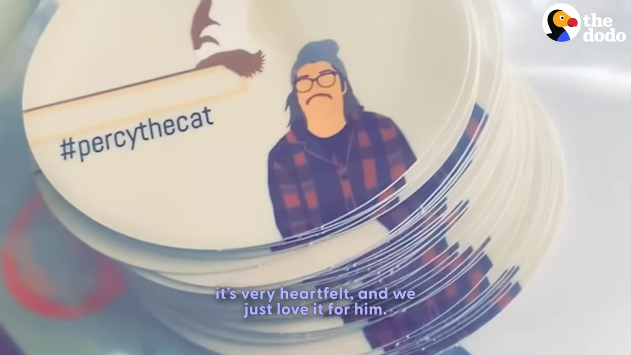 A stack of circular stickers featuring an illustration of a man with glasses and a beanie next to a cat's paws hanging over a ledge, with the text '#percythecat'.