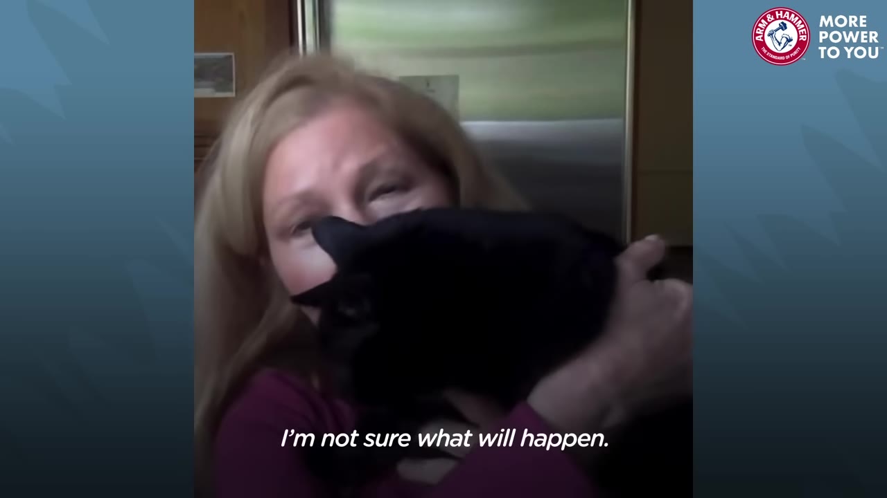 A woman with blonde hair holds a black cat close to her face while looking at the camera.