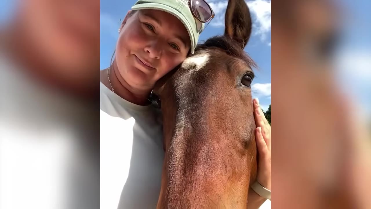 A smiling woman wearing a green cap leans her head affectionately against a brown horse with a white star on its forehead.