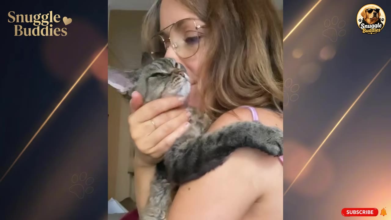 A woman wearing glasses gently holds and kisses a tabby cat, who rests its head in her hand with its eyes closed.