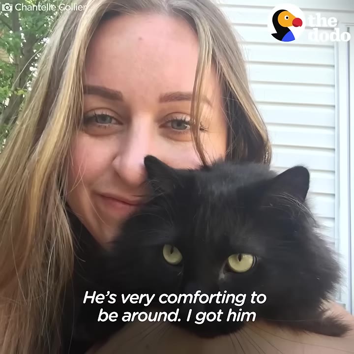 A close-up selfie of Chantelle smiling as she holds her fluffy black cat close to her face.