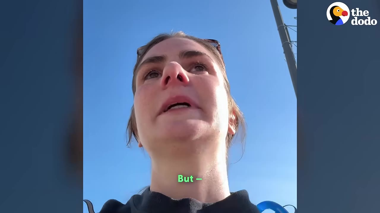 A close-up shot of a woman looking up with a tearful, distressed expression against a clear blue sky.