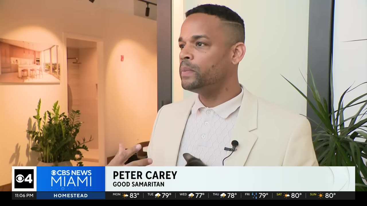 A man identified as Peter Carey in a light-colored suit jacket and polo shirt speaks during an interview.