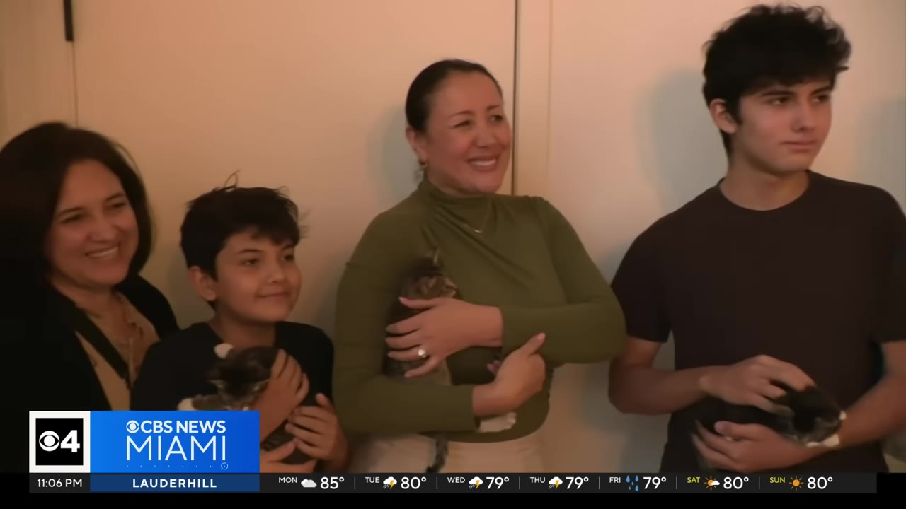 A smiling group of people, including two women and two boys, holding rescued kittens in their arms.