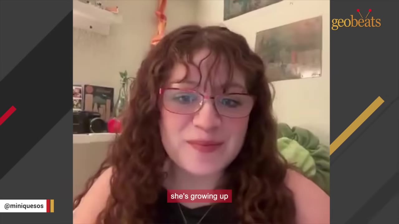 A woman with curly brown hair and glasses speaking directly to the camera.