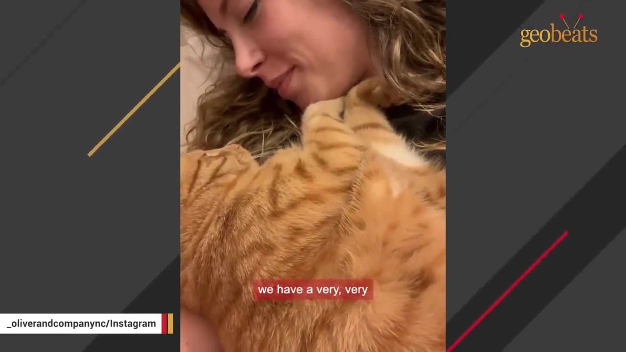 A close-up shot of a smiling woman cuddling an orange tabby cat close to her chest.