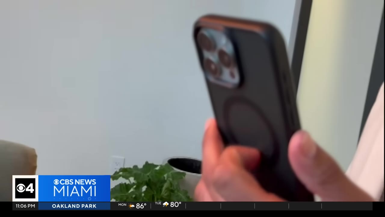 A close-up of a person's hand holding a smartphone in a black case.