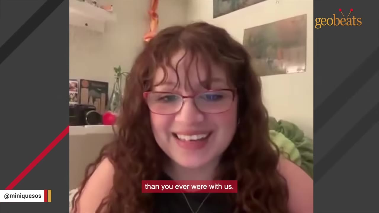 A woman with curly brown hair and glasses smiling warmly while speaking.