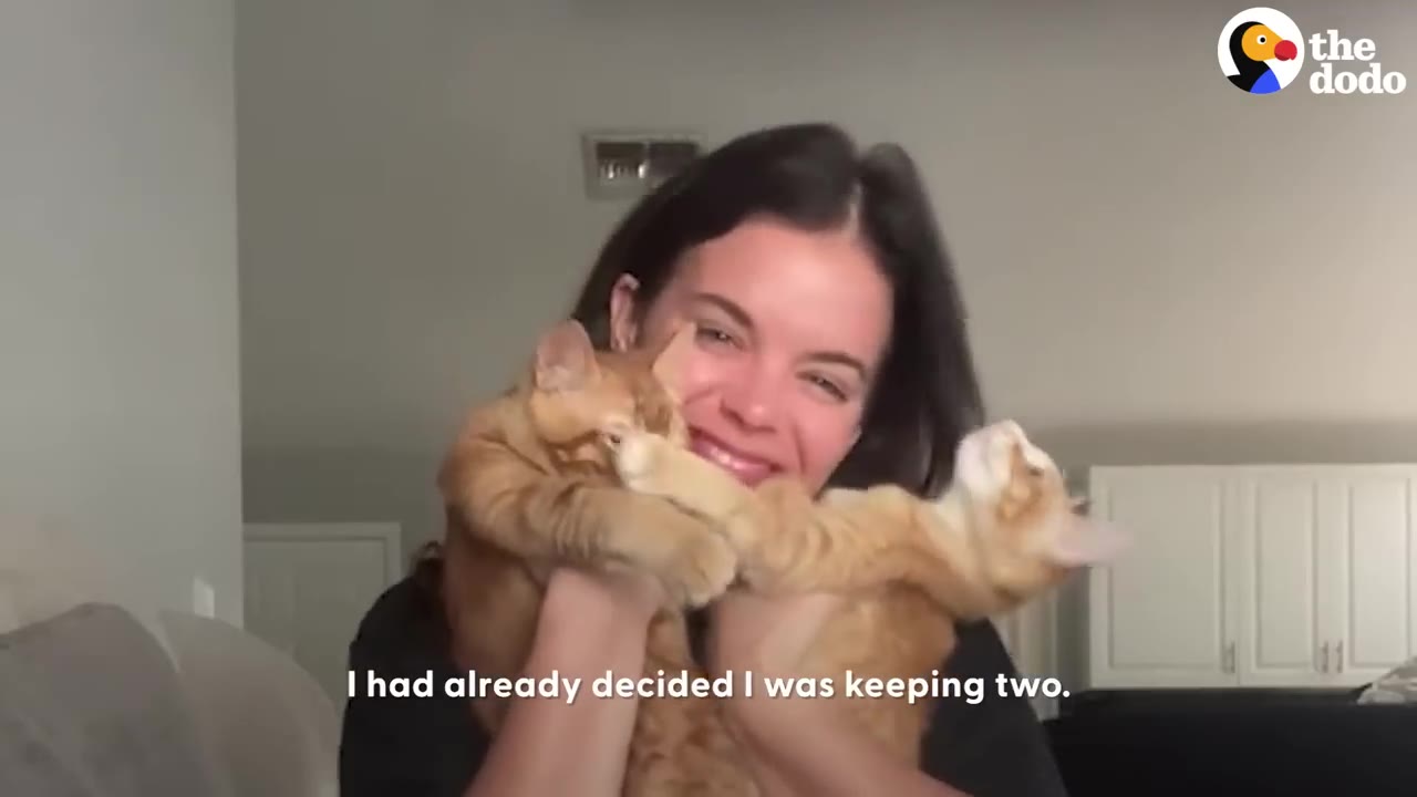 A smiling woman holding two orange kittens close to her chest.