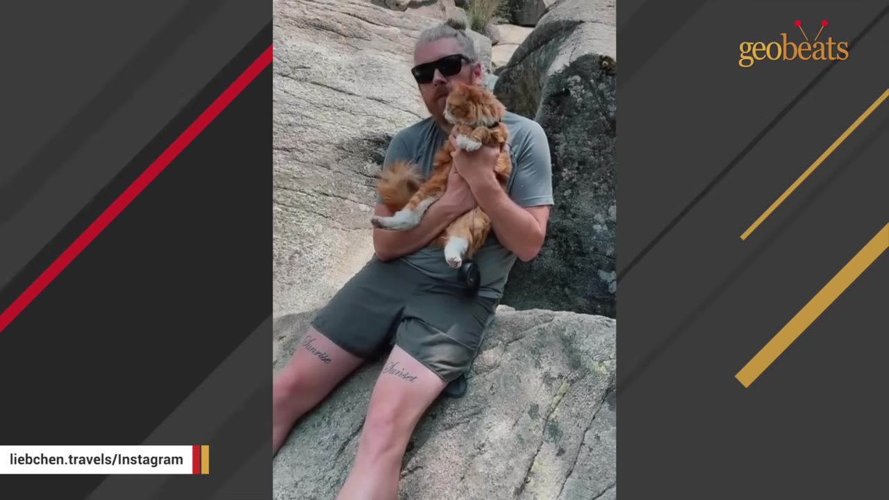 A man with sunglasses sits on a large rock holding a fluffy orange cat in his arms.
