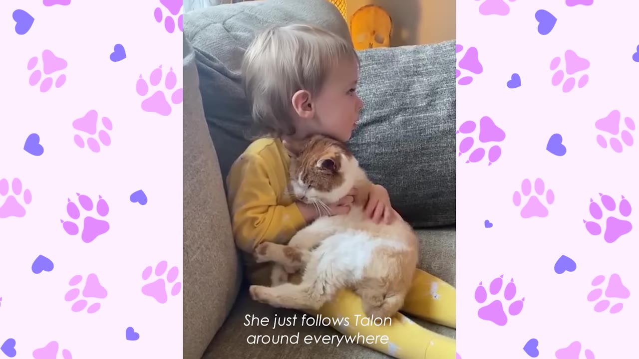 A young child in yellow pajamas sits on a grey couch, gently hugging a fluffy orange and white cat resting in their lap.